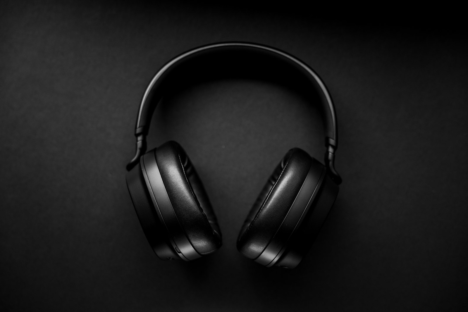 Black over-ear headphones viewed from above on a dark surface.